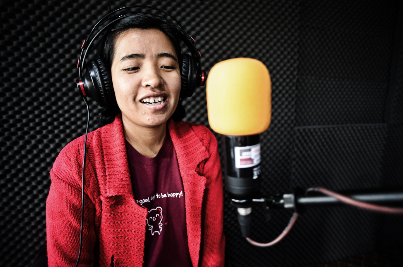 Woman journalist from Myanmar in a recording booth with a microphone and headphones